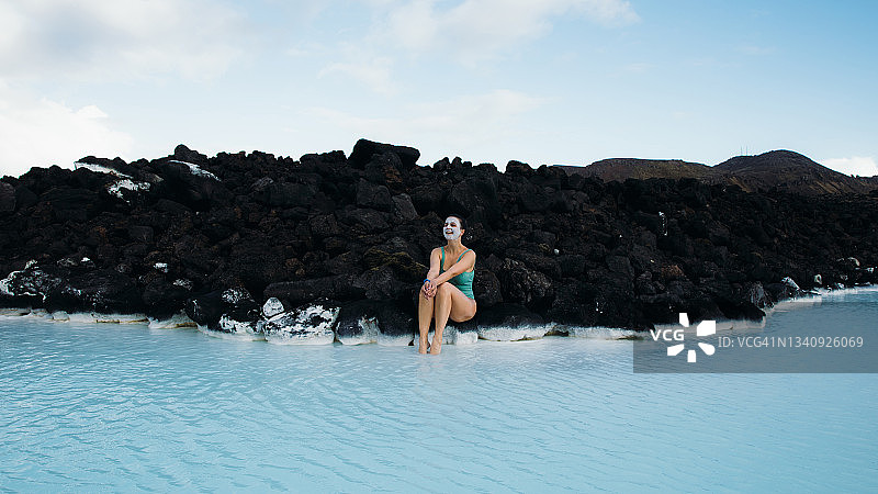 在冰岛碧绿水疗池中享受一天的年轻女人图片素材