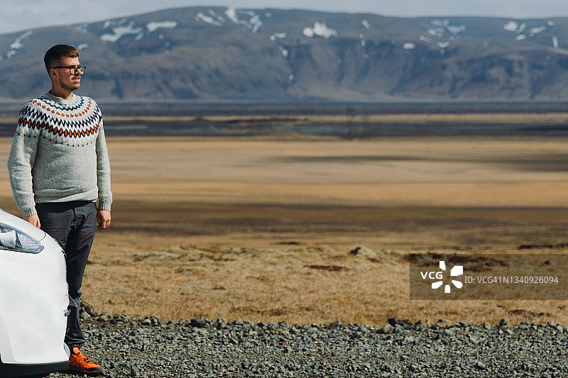 身穿传统羊毛衫的男人在冰岛山区享受公路旅行图片素材