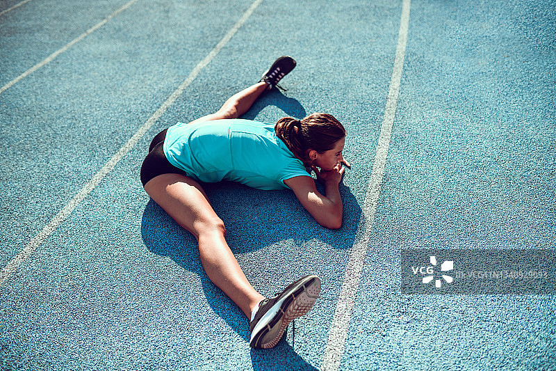 女运动员在跑道上进行劈叉练习图片素材