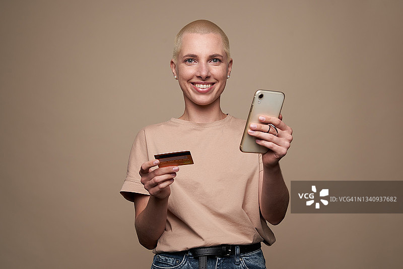 拿着手机和信用卡的金色短发年轻女人图片素材