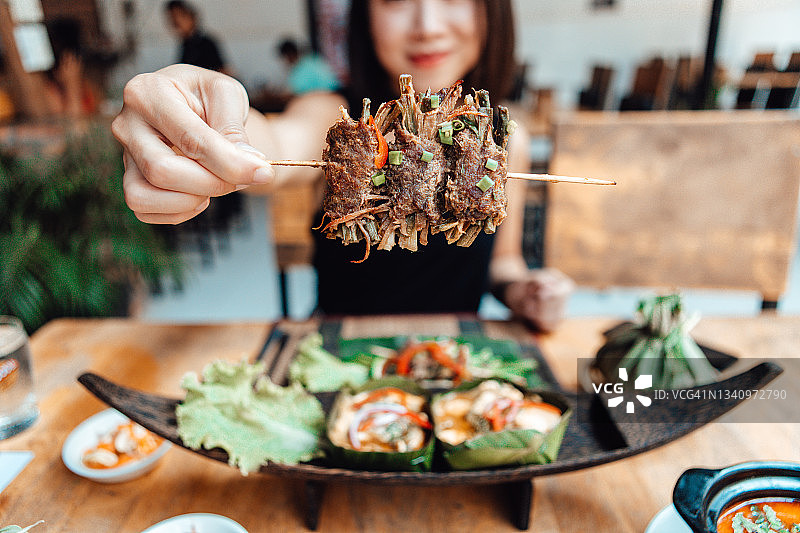在当地泰国街头食品摊位分享正宗泰国食物的年轻女人图片素材