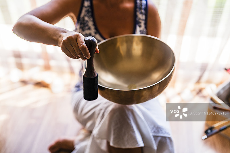 女声音治疗师在工作室用槌子演奏铜碗图片素材