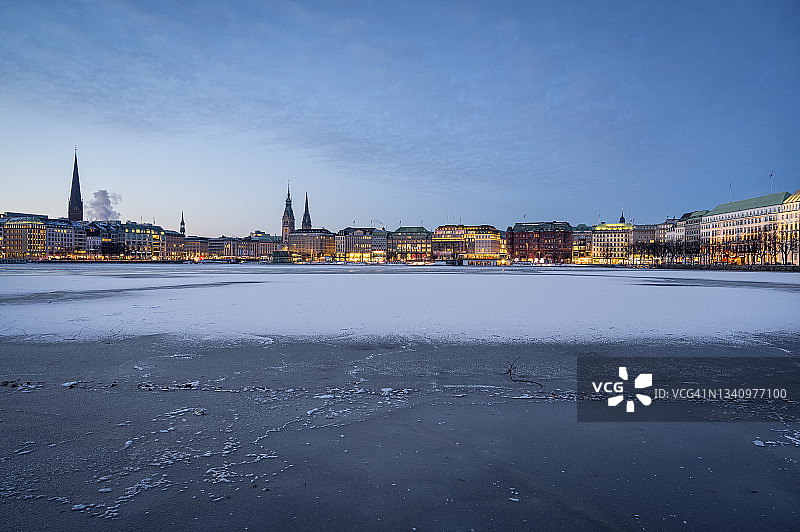 德国汉堡：黎明时分内阿尔斯特湖冰冻的湖面，城市天际线为背景图片素材