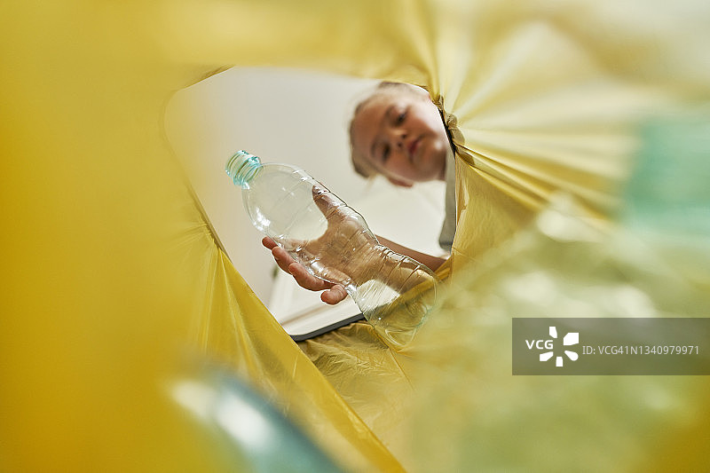 女孩将塑料瓶扔进垃圾袋图片素材