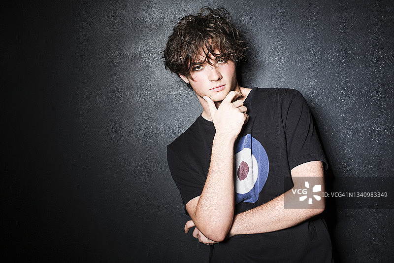 黑色背景下，手托下巴的青少年男孩图片素材