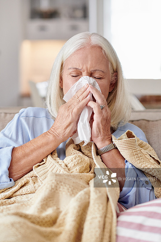 老妇人在家因生病而擤鼻涕图片素材
