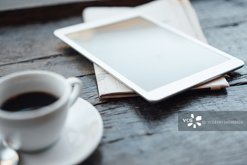 咖啡馆桌上的平板电脑、咖啡杯和报纸图片素材