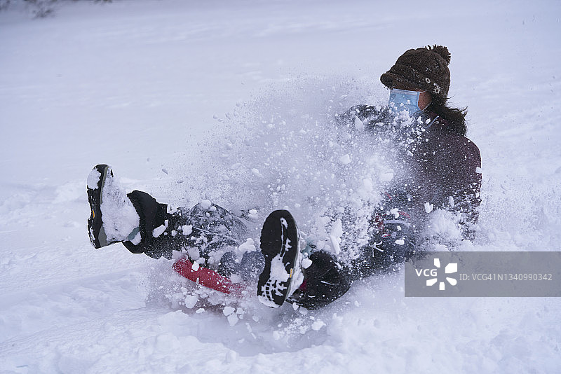 戴着面具的女人在雪地里滑雪橇的侧视图图片素材