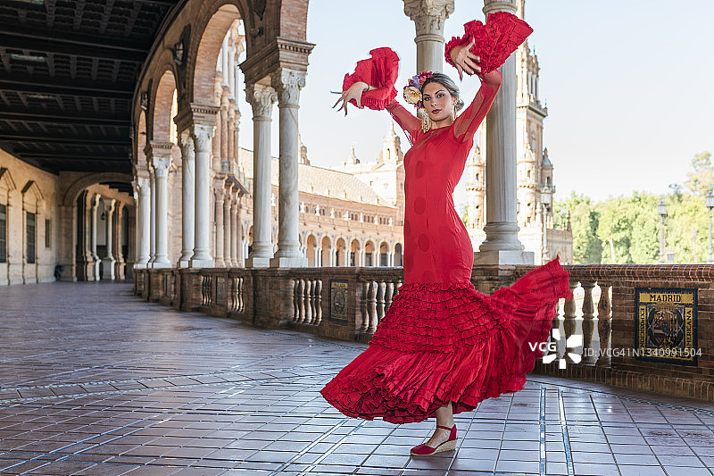 在西班牙塞维利亚西班牙广场的人行道上，举手跳舞的弗拉门戈女艺术家图片素材