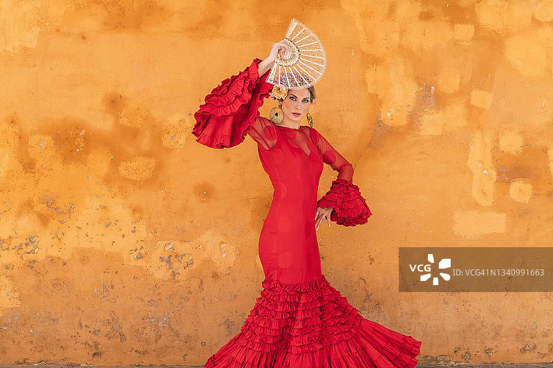 手持扇子的弗拉门戈舞女郎站在墙前图片素材