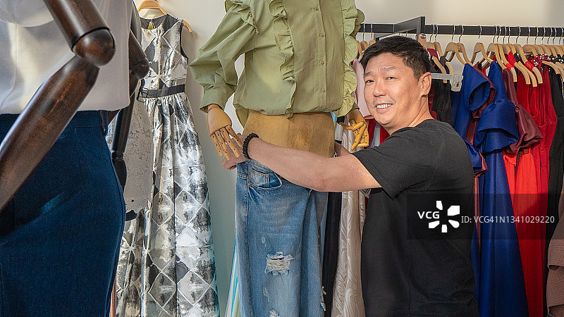 亚洲男时装设计师在人体模型上测量图片素材