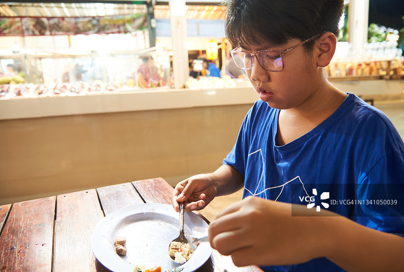 男孩在泰国街头市场吃东西图片素材