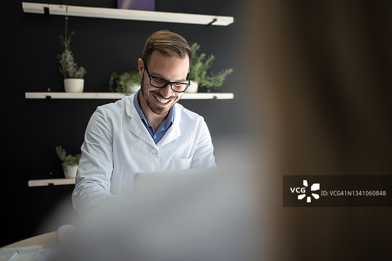 医生在办公室与使用笔记本电脑的病人交谈图片素材