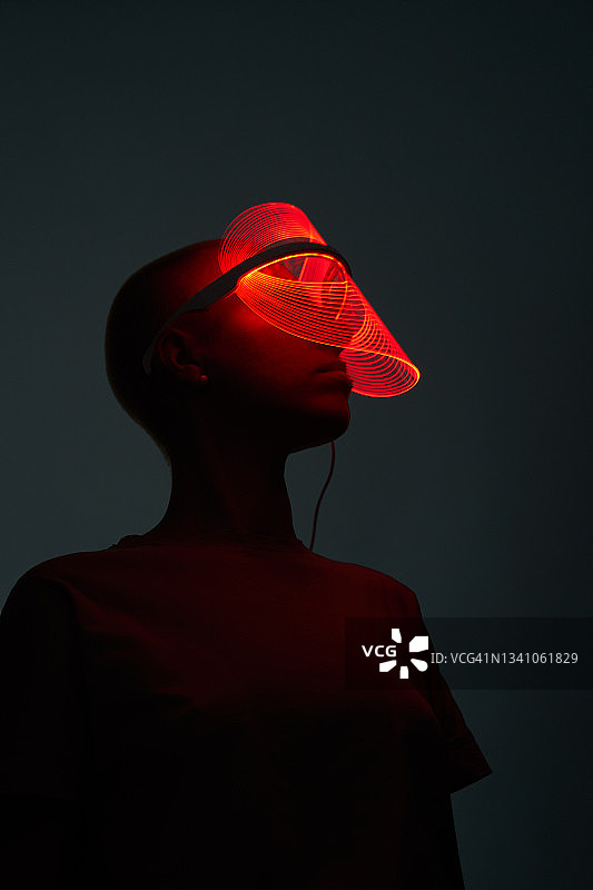 佩戴红色LED美容面罩的年轻女子未来感照片图片素材