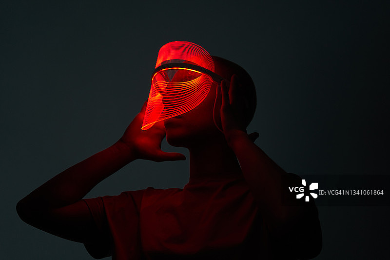 佩戴红色LED美容面罩的年轻女子未来感照片图片素材