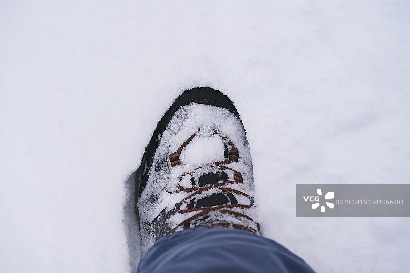 穿着雪地靴站在雪地里的人的腿部特写图片素材