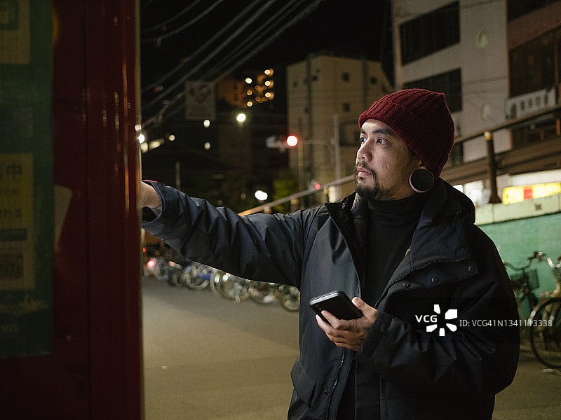 男人在自动售货机上选择饮料。图片素材