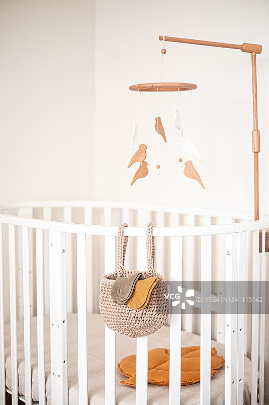 婴儿房特写：白色婴儿床和悬挂的摇铃图片素材