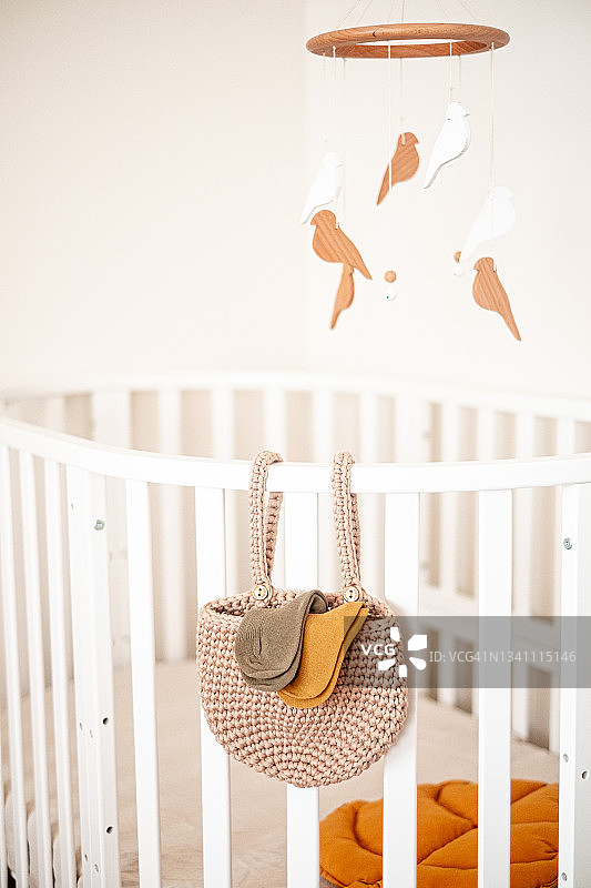 婴儿房特写：白色婴儿床和悬挂的摇铃图片素材