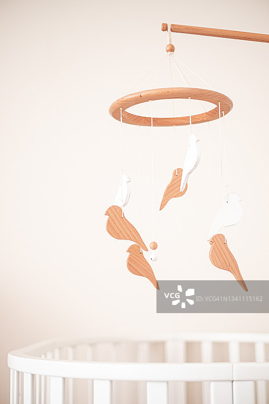 婴儿房特写：白色婴儿床和悬挂的摇铃图片素材