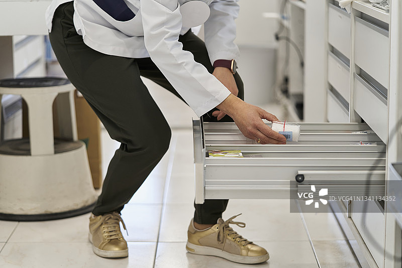 人蹲下从抽屉里拿金色鞋子图片素材