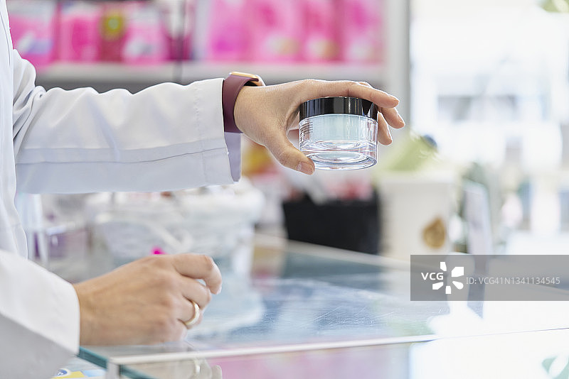 用左手拿起带黑色盖子的小玻璃罐的人图片素材