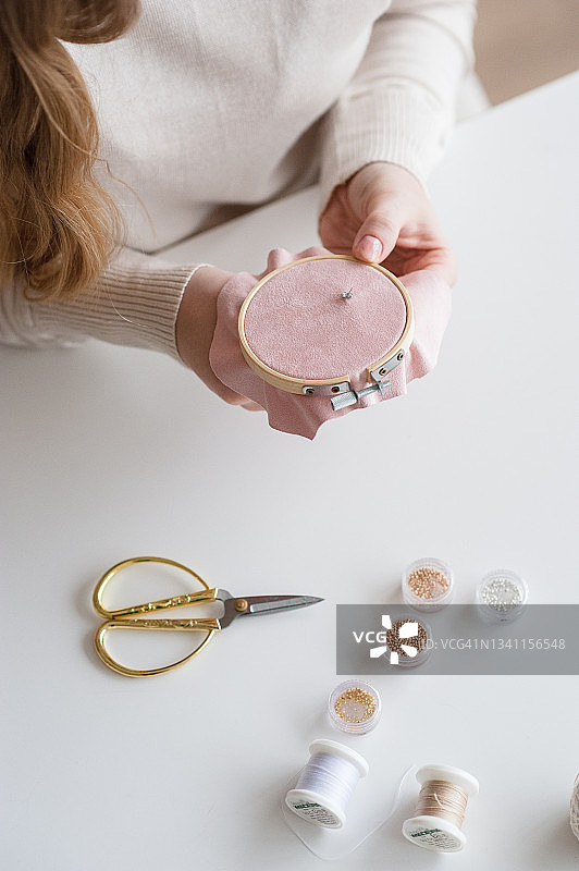 女手工艺人在粉色绣绷上珠绣图片素材