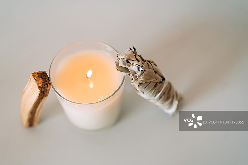 圣木、燃烧的蜡烛和白色鼠尾草灰色背景构图（香薰和仪式用品，顶视图和微距）图片素材