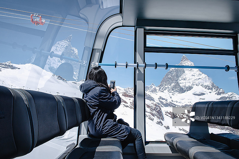 女游客在缆车上用手机拍照欣赏山顶风光图片素材
