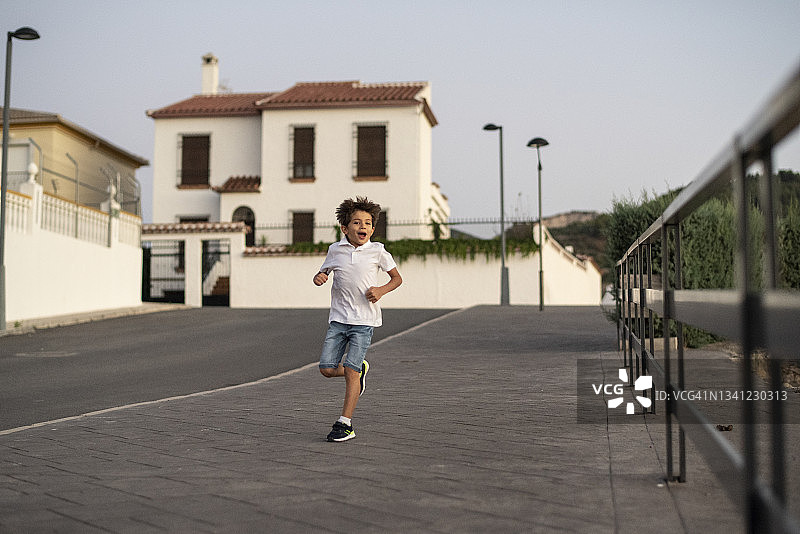 男孩在夜晚的社区人行道上奔跑图片素材