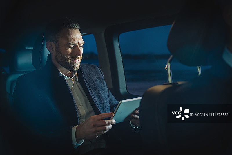 在上班途中在车里用平板电脑工作的商人图片素材