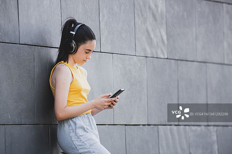 快乐的青少年使用蓝牙耳机和智能手机听音乐图片素材