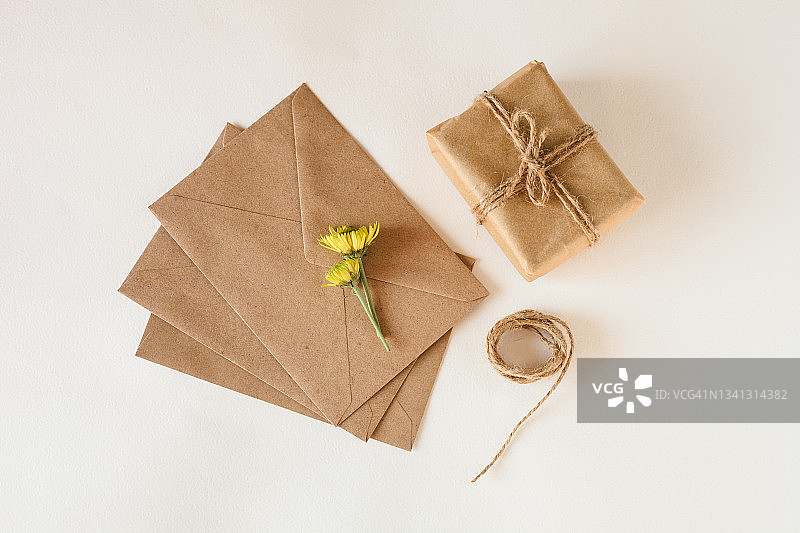 白色背景上的牛皮纸信封、鲜花和礼品盒图片素材