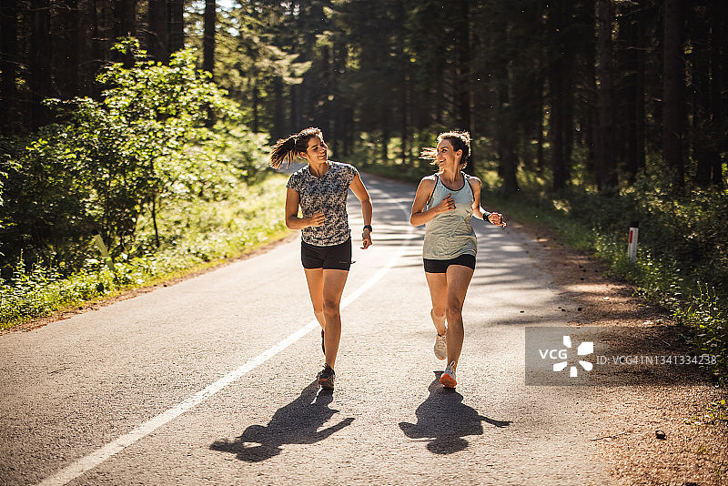 女运动员在森林的道路上跑步图片素材