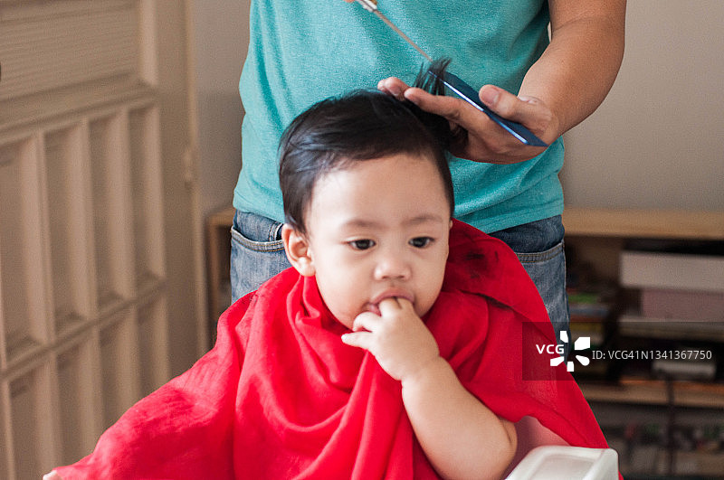 疫情期间，一位东南亚父亲在家为儿子理发图片素材
