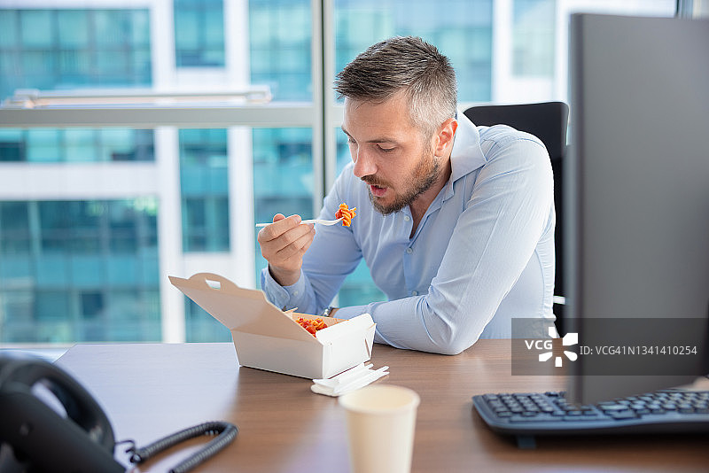 年轻办公室职员在工作间隙吃外卖图片素材
