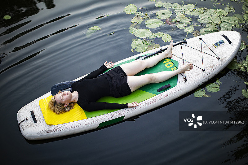 年轻女子在桨板上练习瑜伽图片素材