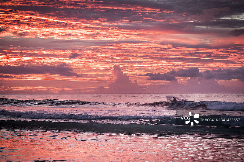 日落时分，冲浪者在夏威夷群岛瓦胡岛海域乘风破浪图片素材