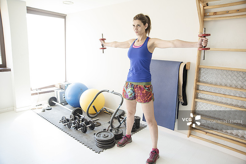 成年女人在西班牙巴塞罗那的健身房用哑铃训练图片素材