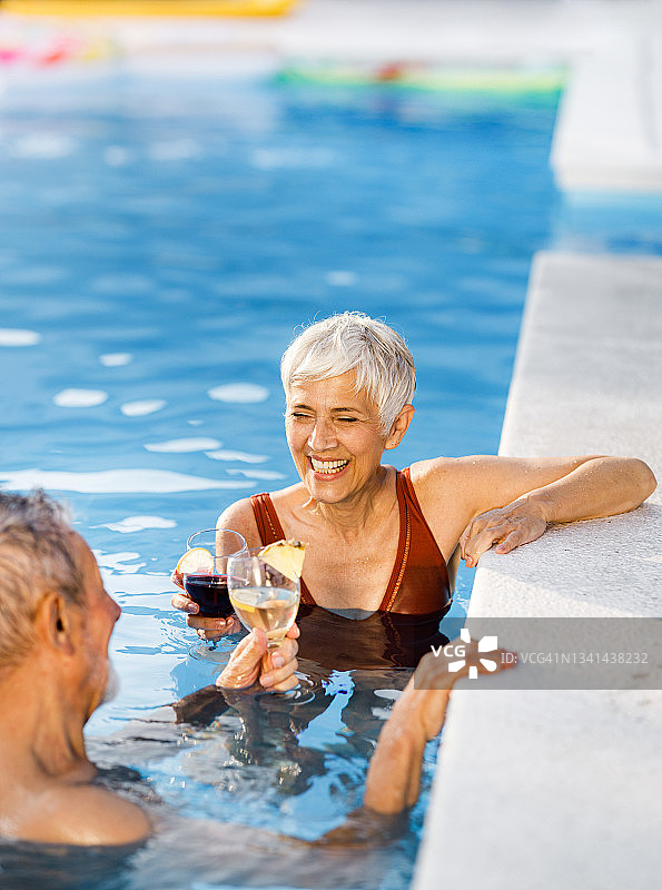 快乐的中年夫妇在泳池边举杯庆祝图片素材