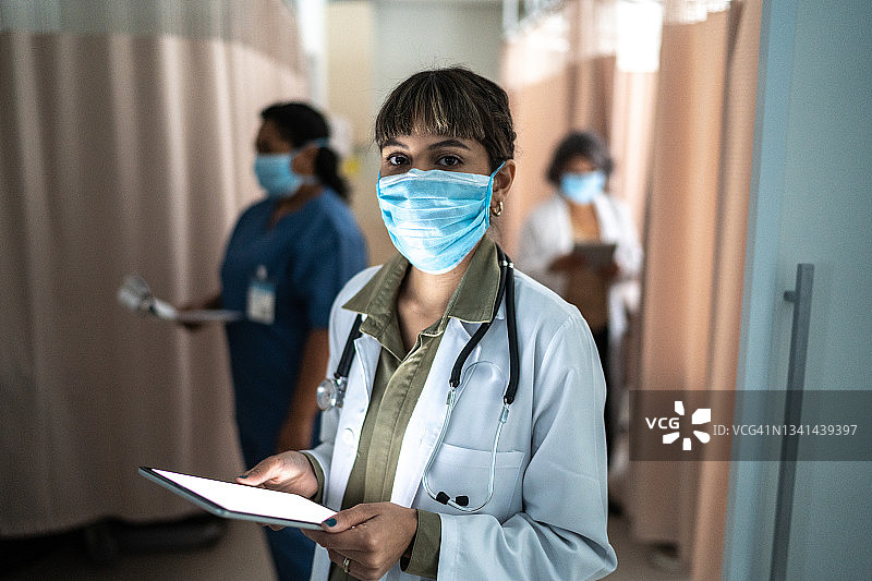 医院里与同事一起工作的自信医生肖像 - 戴着防护口罩图片素材