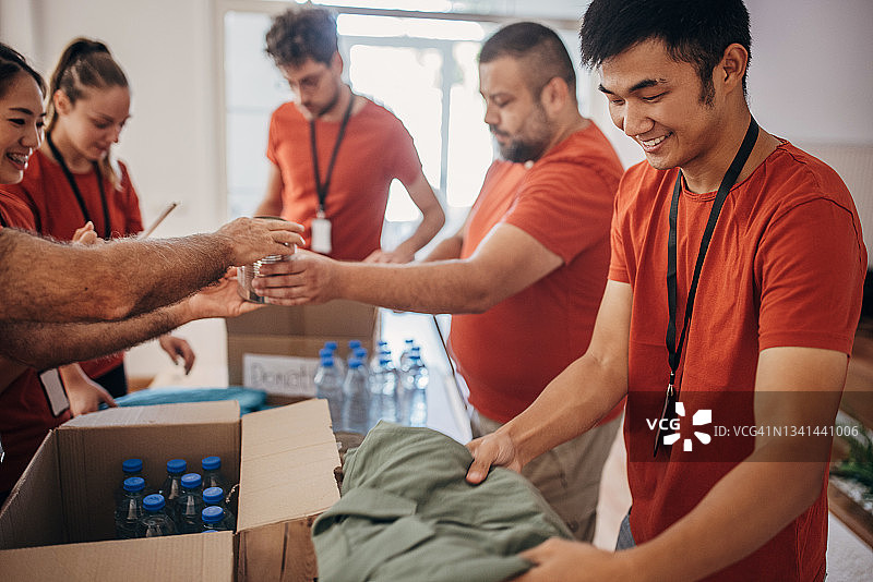 志愿者团队在捐赠中心分享和包装食物、衣服和水，用盒子装好送给有需要的人图片素材