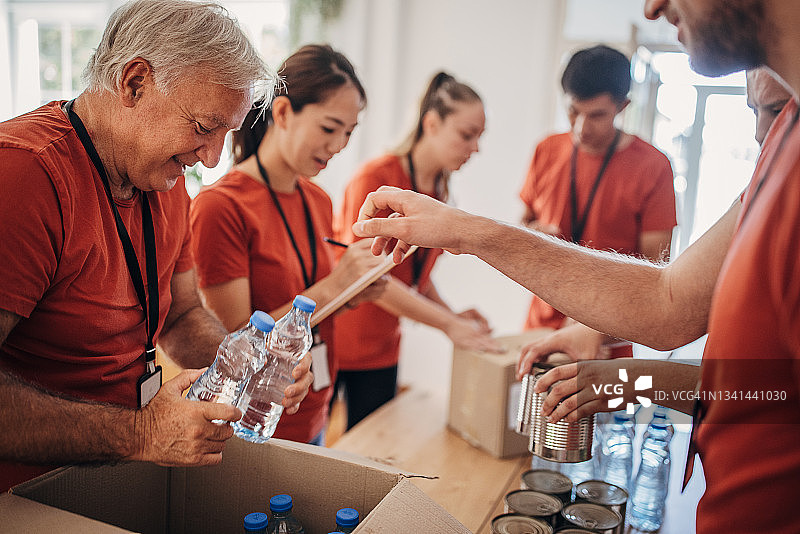 志愿者团队在捐赠中心分享和包装食物、衣服和水，用盒子装好送给有需要的人图片素材