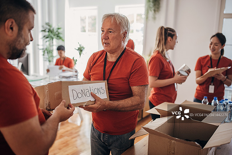 志愿者团队在捐赠中心分享和包装食物、衣服和水，用盒子装好送给有需要的人图片素材