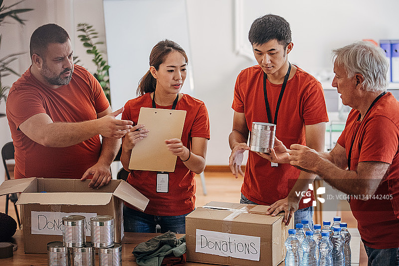 志愿者团队在捐赠中心分享和包装食物、衣服和水，用盒子装好送给有需要的人图片素材