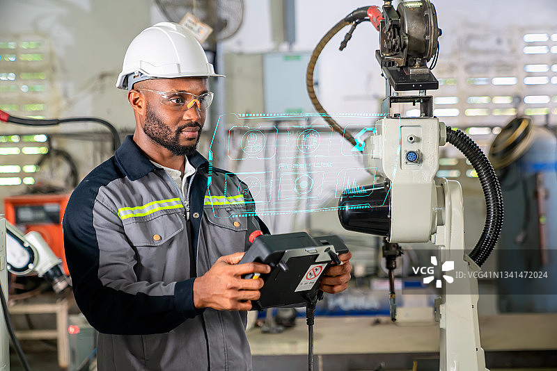 机器人教练教机器人手臂进行金属焊接，现代工厂的工业制造流程与机器人控制，工业4.0概念图片素材