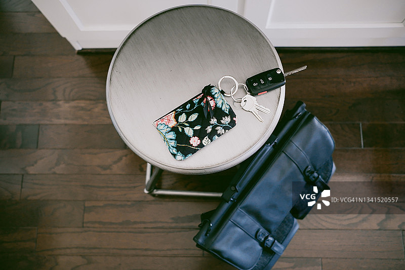 放在吧台凳上的钥匙和地上的工作包图片素材