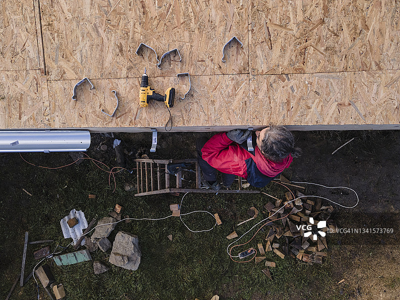 DIY家居改善：男子修理谷仓屋顶的鸟瞰图图片素材