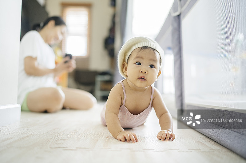 年轻的亚洲单身母亲鼓励女儿尝试爬行图片素材