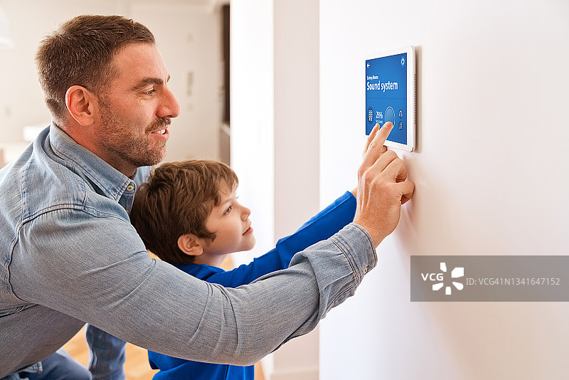 父亲和儿子在家用平板电脑控制智能设备图片素材